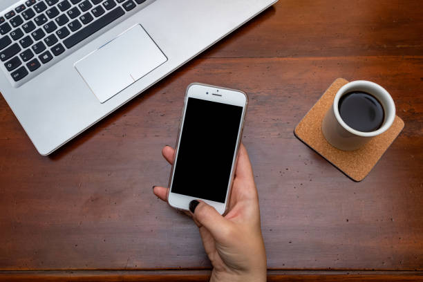 istock Woman hand holding smartphone on wooden desk while taking a break 1125690721