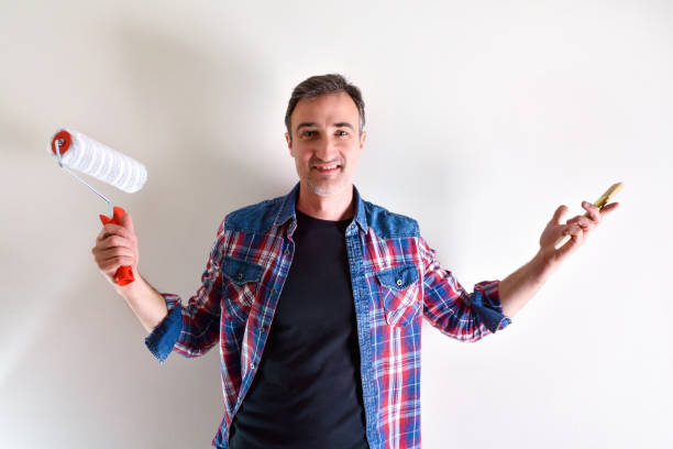 istock Smiling man with painting tools and white wall behind 1125691615