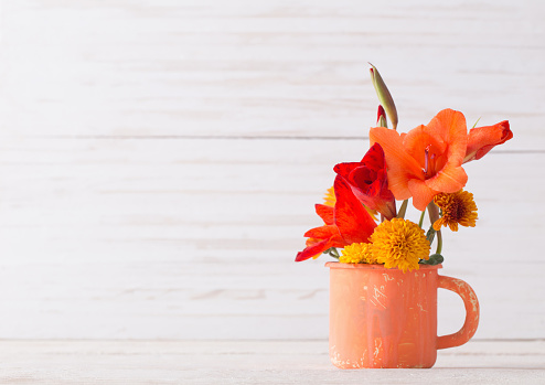 flowers in orange old cup on wooden table