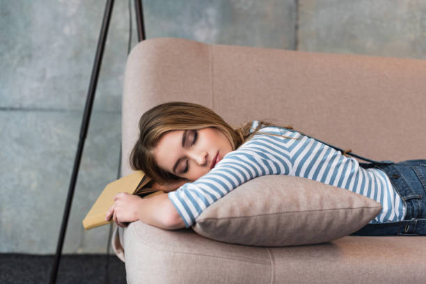 istock young beautiful woman sleeping on sofa with book in hand 1125698286