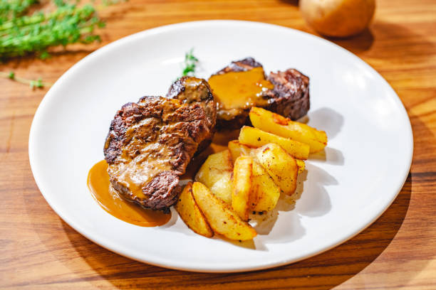istock Grilled beef steak with potato wedges on white plate. Close up 1125699146