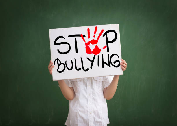 Violence in today schools Boy holding a sign with red palm print and text stop bullying bullying photos stock pictures, royalty-free photos & images