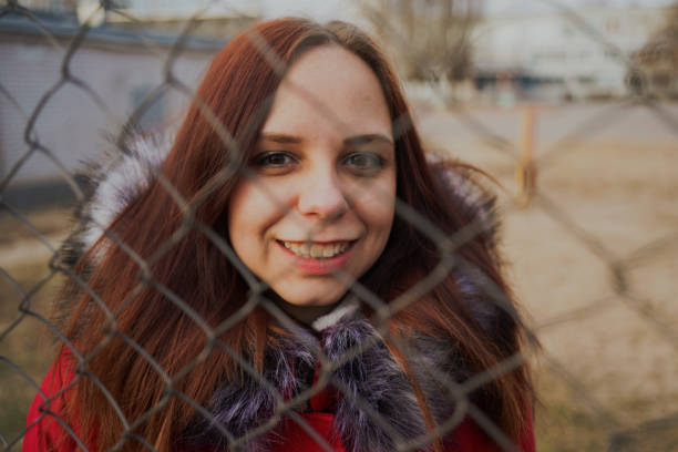 istock Happy beautiful young girl in a red jacket posing outside on a cloudy day. 1125700611