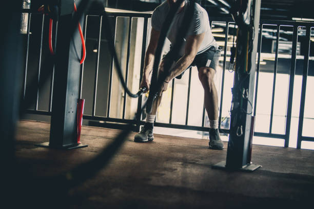 istock Muscular man doing battle rope workout in the gym 1125700922