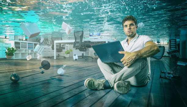 istock Portrait Of Businessman Using Laptop While Office Sunk In Water 1125700933