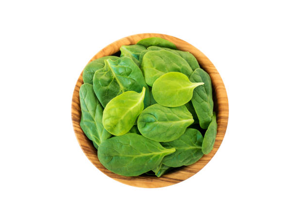 istock Spinach leaves in the olive wood bowl top view isolated on white 1125701534