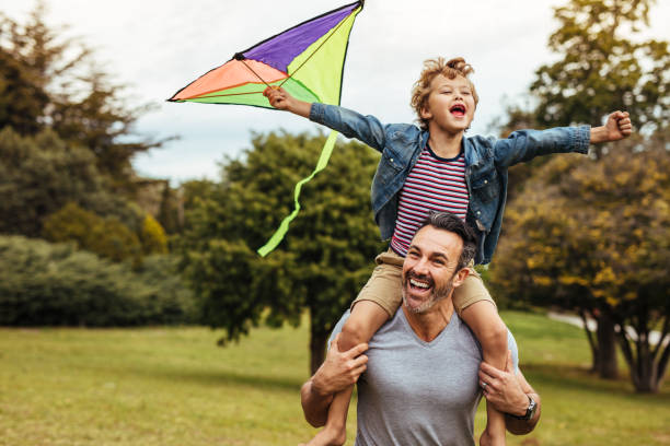 istock Smiling boy on fathers shoulders playing with kite 1125703685