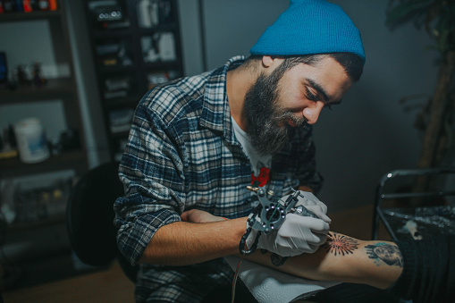 Man tattoo artist making tattoo on a man's arm