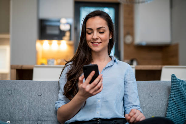 istock Young woman sitting on the couch and using smart phone 1125710397