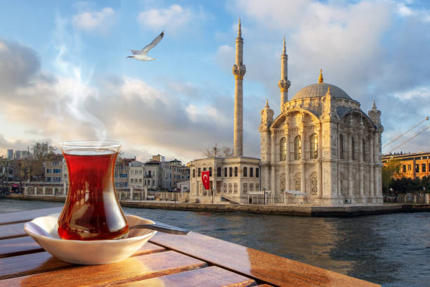 A cup of Turkish tea in a traditional glass against the background of the Medgidiye Mosque in Istanbul stock photo