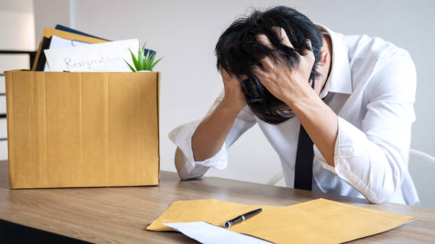 テーブルに座っている頭を手にした心配している従業員 - うつ病 休職 ストックフォトと画像