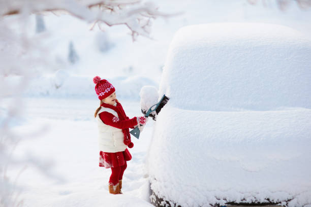 istock Child brushing off car. Kid with winter snow brush 1125710801