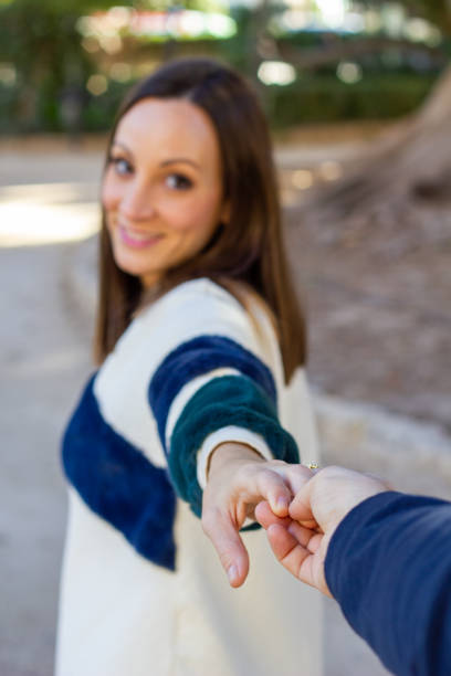 istock Young girl pulls someone's hand while walking through an urban park 1125712209