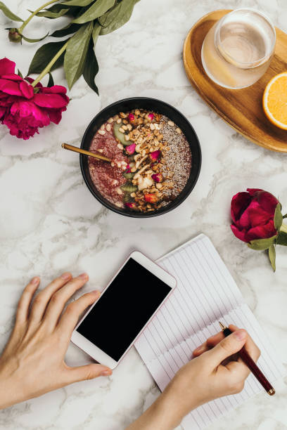 istock Flatlay of woman's hands with notebook and smartphone, vegan smoothie bowl with chia pudding 1125717403