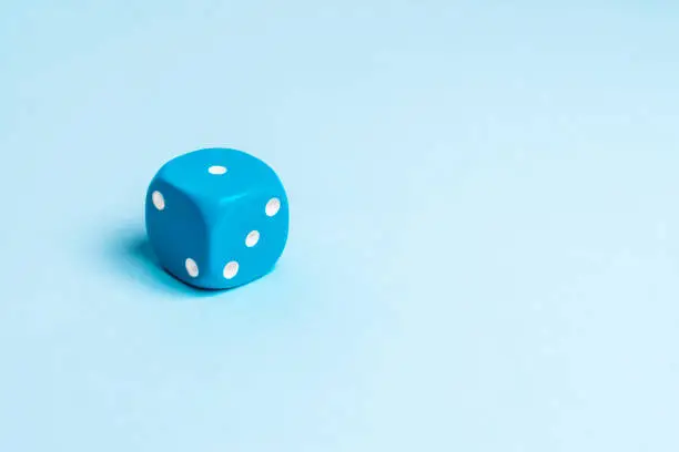 Photo of A blue dice on a uniform background