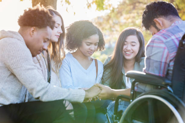 College friends praying together Diverse group of college friends hold hands and pray together on campus. christianity stock pictures, royalty-free photos & images