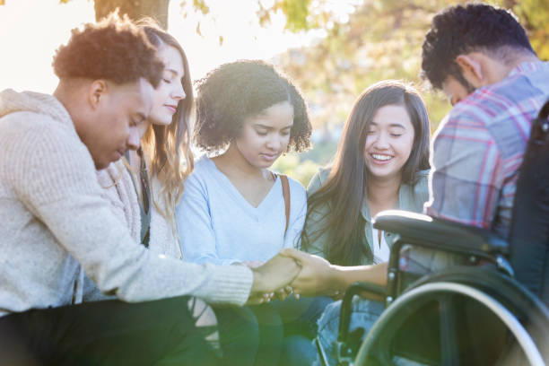 College friends praying together Diverse group of college friends hold hands and pray together on campus. religion god stock pictures, royalty-free photos & images