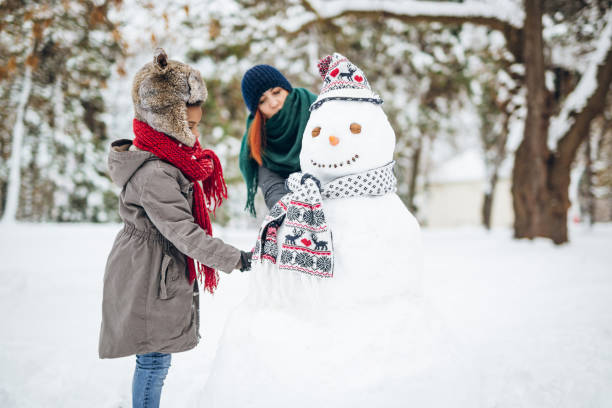 istock Mother and daughter making a snowman 1125722918