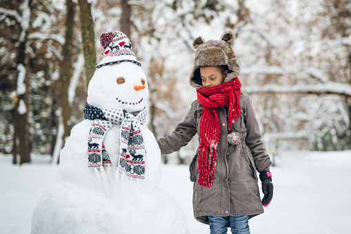 Young girl enjoying winters magics making a snowman