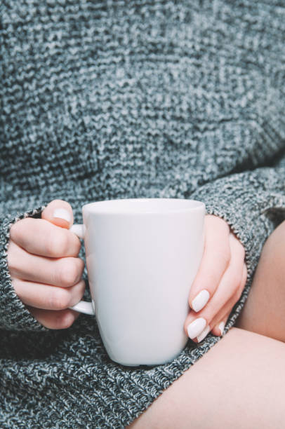 istock A woman holding a white mug in her hands. Template for design or text 1125729609