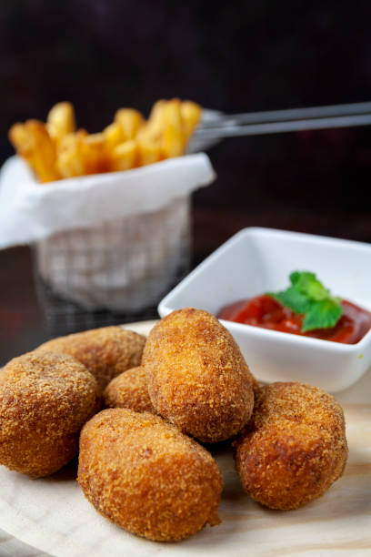 istock Croquettes on a wood plate with fried tomate and chips 1125731298