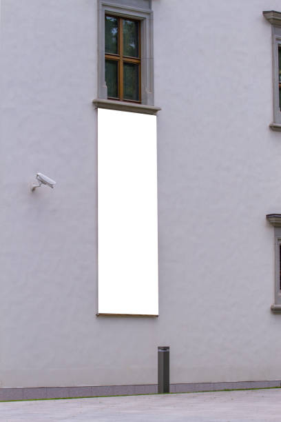 istock Mock up. Blank white vertical banner on building facade. Empty advertising flag mock up on the wall 1125733943