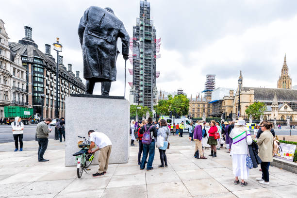 statua dell'ex primo ministro winston churchill in parliament square con molte persone in piedi accanto al big ben - winston churchill foto e immagini stock