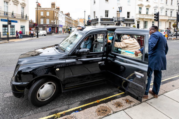 역사적인 건축과 블랙 택시 택시에 들어갈 여자를 돕는 pimlico 또는 빅토리아 거리도로 - hackney 뉴스 사진 이미지