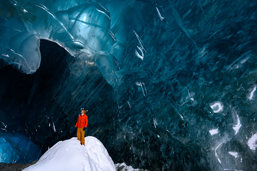 Man exploring a stunning glacial ice cave