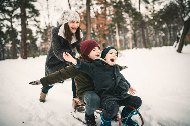 jungen mit mama spaß auf einem schlitten - winter family child snow stock-fotos und bilder