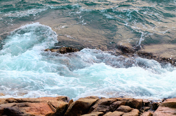 istock Foaming sea water hits stone beach, wave and beach 1125741639