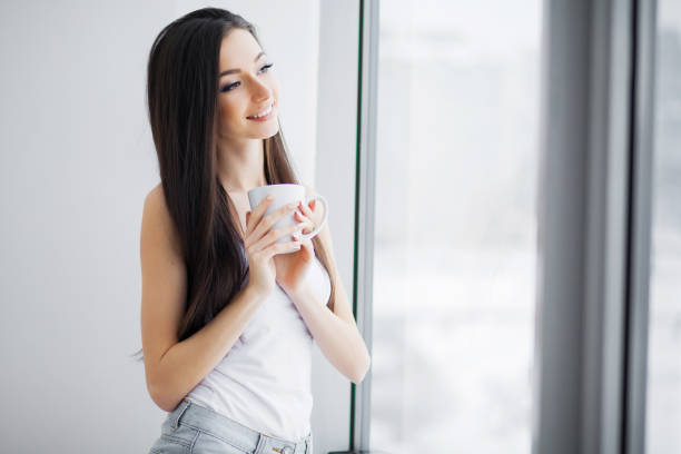 istock Woman in shorts at window in morning 1125742321