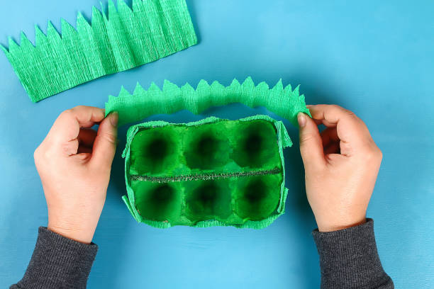istock DIY basket Easter egg from cardboard tray, crepe paper, chenille stem on blue background. 1125742621