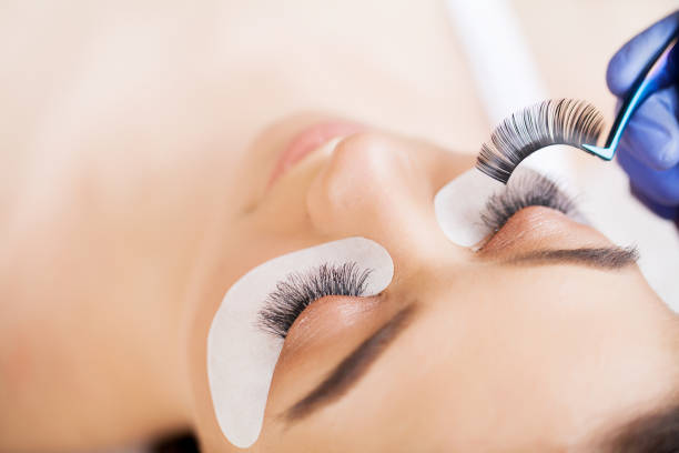 istock Eyelashes extensions. Fake Eyelashes. Eyelash Extension Procedure. Professional stylist lengthening female lashes. Master and a client in a beauty salon 1125742735