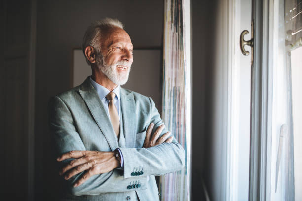 istock Cheerful senior entrepreneur looking through a window on a sunny day 1125744104