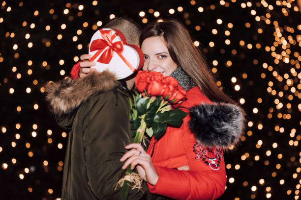 istock Woman is holding a gift box and roses and smiling while hugging  man 1125748276