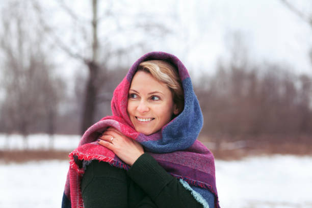 ritratto di un'attraente donna bionda in sciarpa colorata fredda nella foresta invernale innevata. - snow heat adult blond hair foto e immagini stock