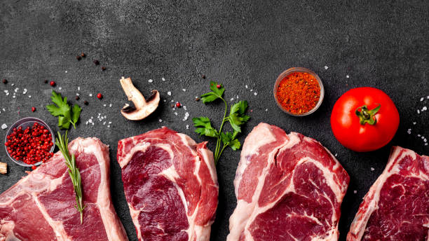 istock Meat raw steaks lie on a black background with vegetables, tomatoes, marasmade, mushrooms. background image. side view, copy space, top view 1125755280
