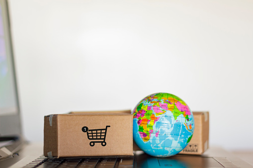 Cartons and earth globe on computer. Worldwide shopping and delivery business concept