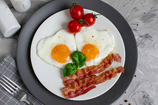 Tasty Fried Egg in the Shape of a Heart Served on a White Plate with Bacon Tomato Basil Pepper Background Valentine Day Breakfast