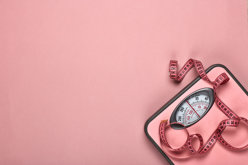 Female fitness still life. Scales and measuring tape on pink background. Mockup. Planning of diet and trainings. Top view with copy space. Healthy lifestyle concept. Slimming