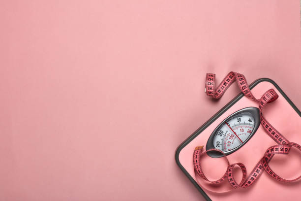 Healthy lifestyle concept. Slimming Female fitness still life. Scales and measuring tape on pink background. Mockup. Planning of diet and trainings. Top view with copy space. Healthy lifestyle concept. Slimming slimming stock pictures, royalty-free photos & images