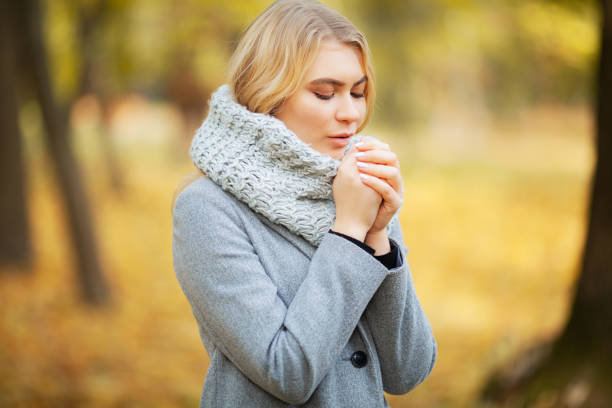 istock Cold autumn. Woman walking in park feeling cold 1125761658