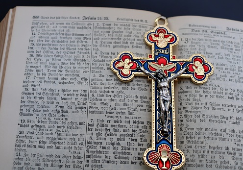 Colorful cross laying in middle of open German Bible. Bible is very old with no copyright or date marked in it