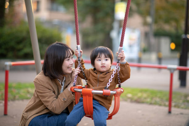 istock Young mother and little son playing swing in public park 1125768908