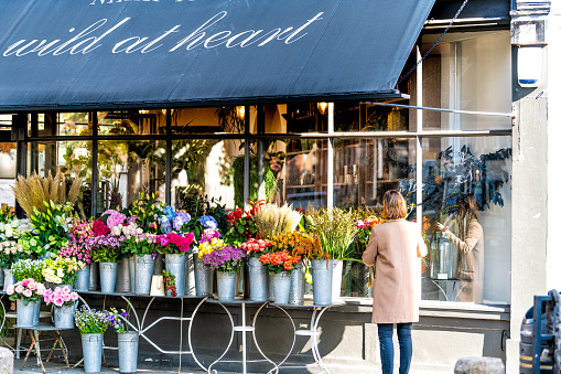 London, UK - September 13, 2018: Street in Pimlico Belgravia area with Wild at Heart Florist flower shop and woman setting up bouquets