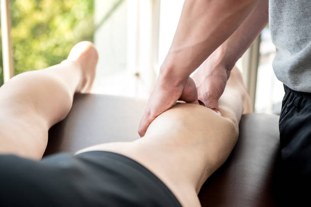 male therapist giving leg massage to athlete patient in clinic - reflexology massaging recovery sport imagens e fotografias de stock