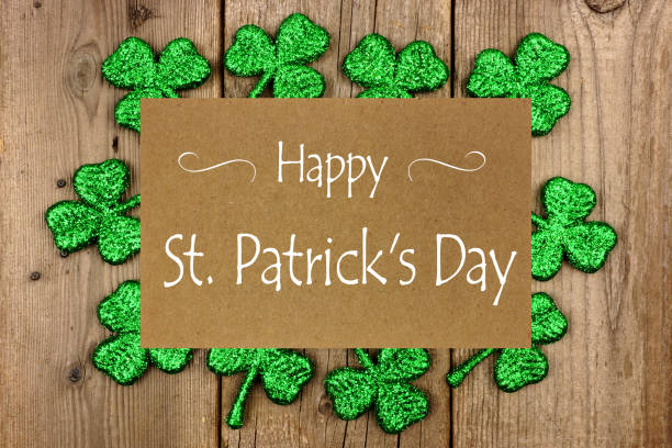 Happy St Patrick Day greeting card with shiny shamrocks over rustic wood Happy St Patrick Day greeting card with frame of shiny shamrocks over a rustic wood background good luck charm photos stock pictures, royalty-free photos & images
