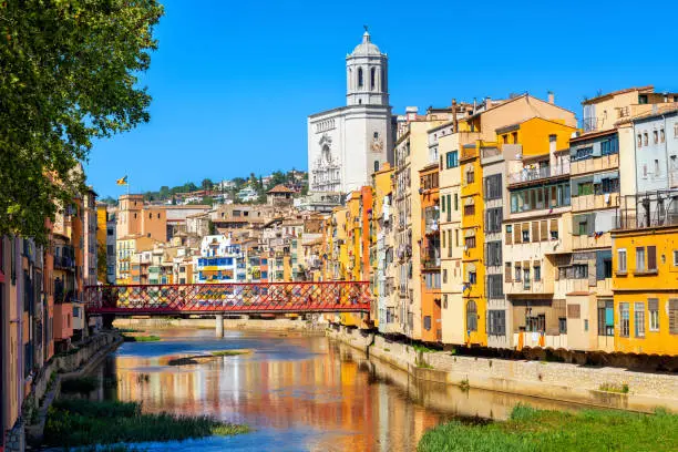 Traditional colorful houses and gothic Cathedral in Girona Old Town, Catalonia, Spain, reflecting in the river on a bright, sunny day