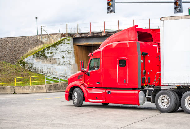 istock Red modern big rig semi truck with semi trailer turning under bridge on intersection 1125792829